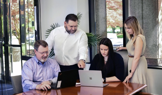 people at a desk looking at laptops